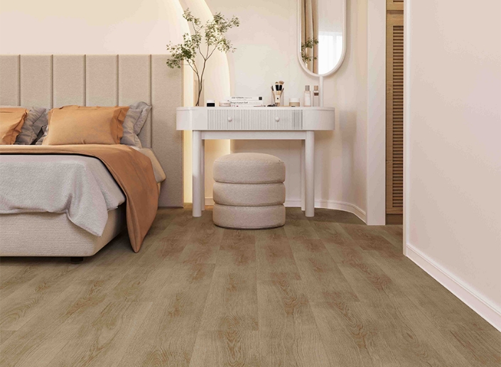 Cozy bedroom with neutral tones, a bed, vanity table, and cushioned stool on wood flooring.