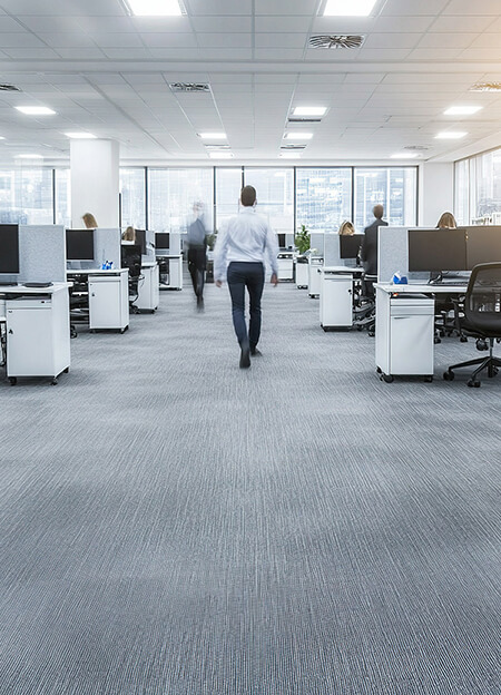 Modern open-plan office with people working at desks and walking through the aisle