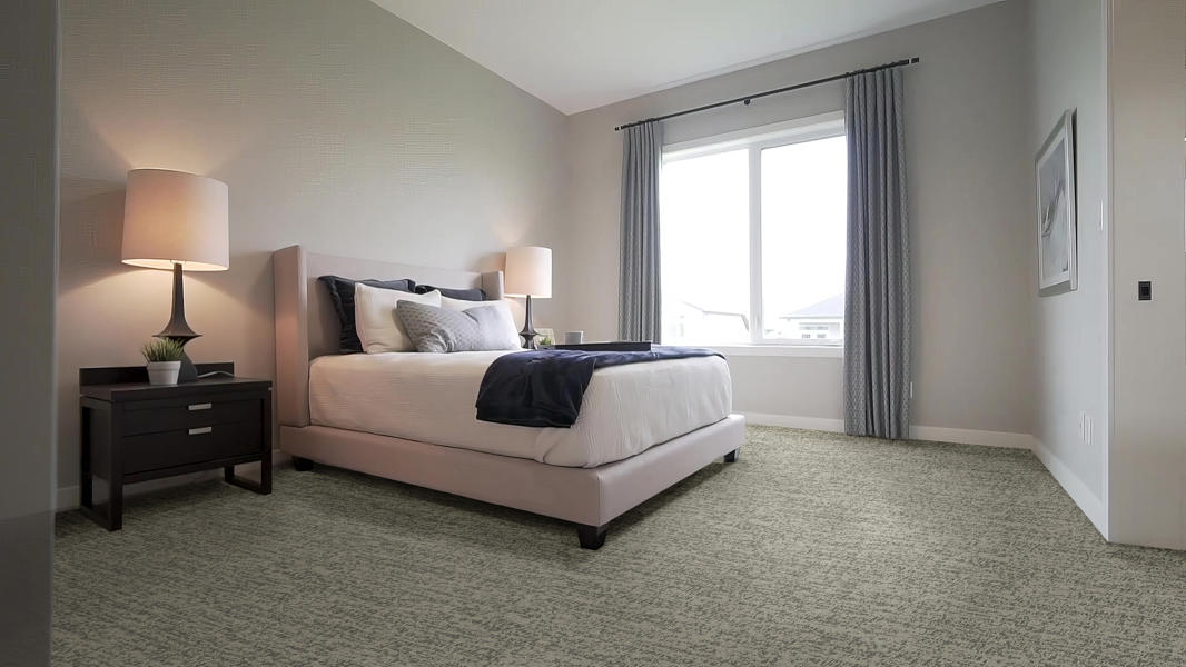 Cozy bedroom with neutral tones, a bed, vanity table, and cushioned stool on wood flooring.