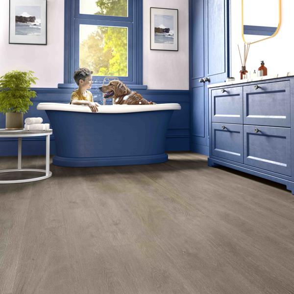 Cozy bedroom with neutral tones, a bed, vanity table, and cushioned stool on wood flooring.
